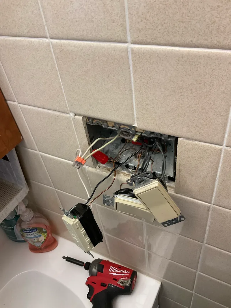 Junction box opened during bathroom outlet and switch replacement in tiled wall