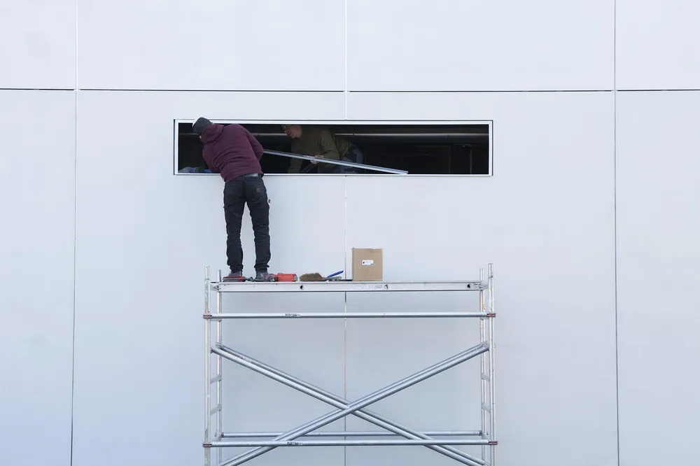 Electricians on a work platform installing equipment on a commercial building