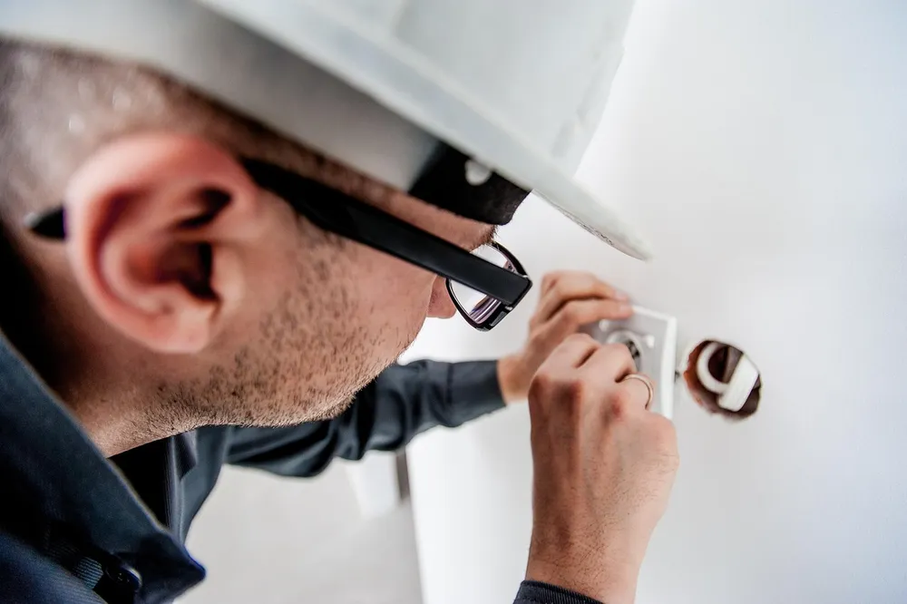 Licensed electrician repairing a wall outlet during a home electrical repair visit