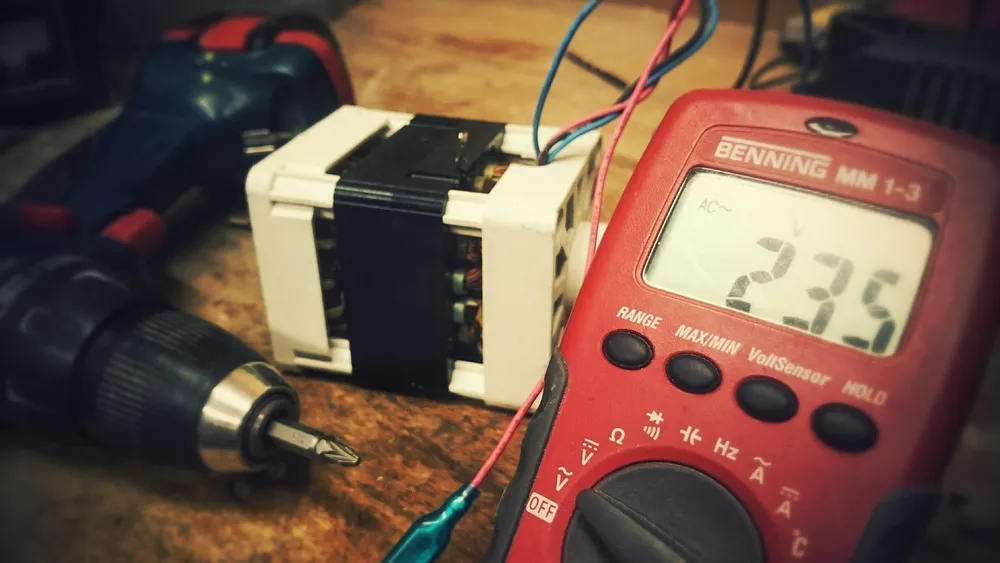 Electrician using a digital multimeter to test wiring during an electrical safety inspection